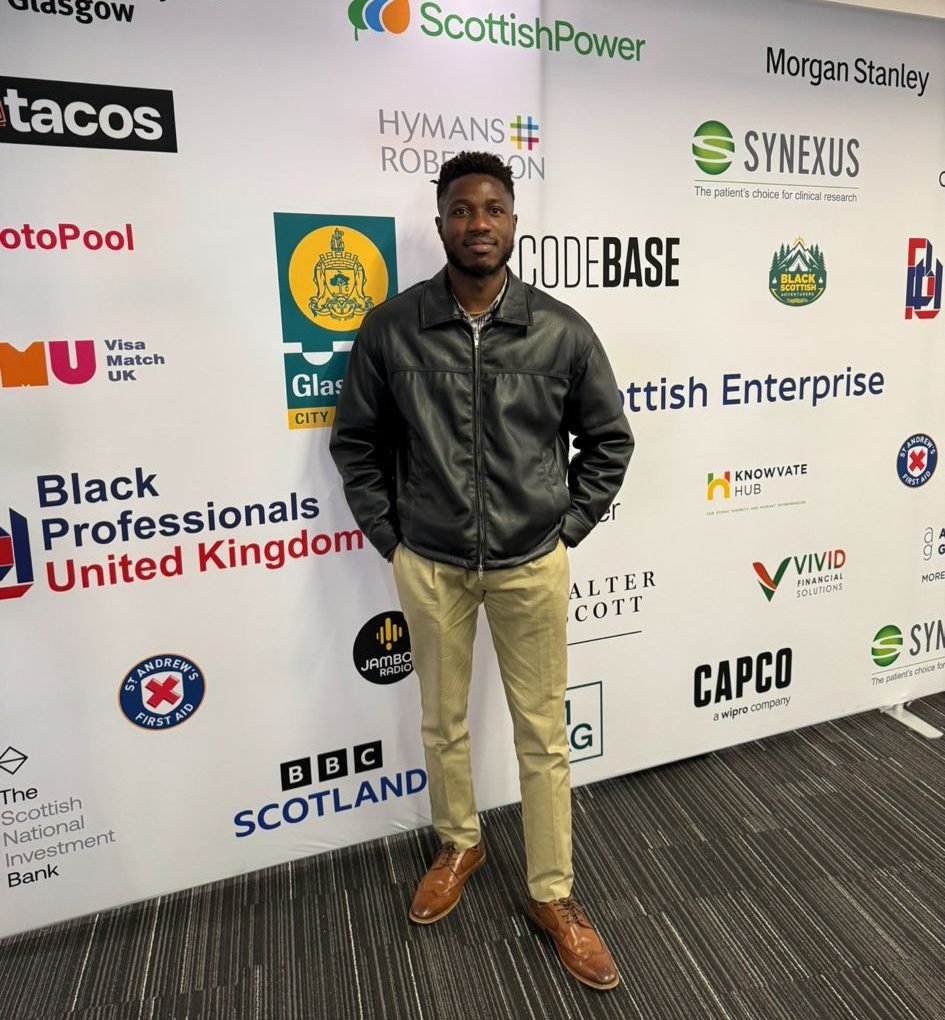Leke Ariyo at a UK tech conference. He is wearing a black jacket and a beige tint trouser, with both hands in pocket